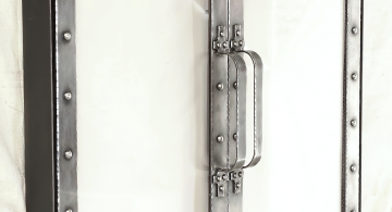 Fireplace doors in antique nickel with polished rivets. These doors fit within a fireplace opening, and rather than having a wire mesh screen, these doors employ fireproof glass giving the project a very tidy overall feel. By Archive Designs.